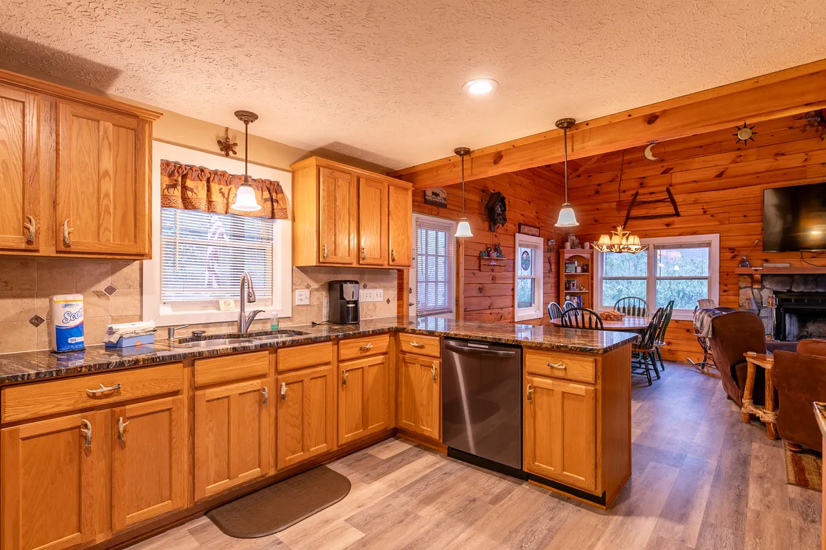 This image highlights a fully equipped kitchen with granite countertops, wooden cabinets, modern appliances, and an adjacent dining area. The design brings an inviting mood, perfect for preparing shared meals or gathering for celebrations.