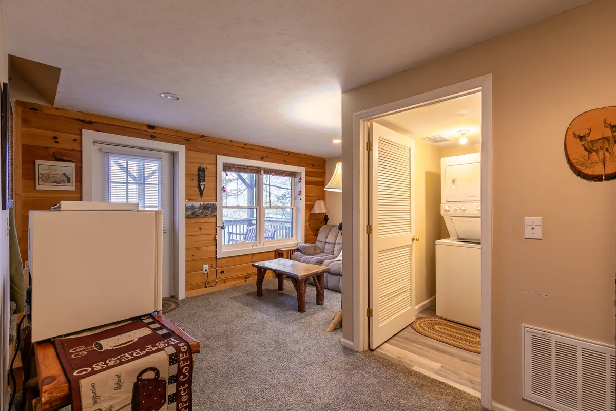 A welcoming interior with wood-paneled walls, a cozy seating area, large windows, and a visible laundry area. The room blends comfort with practicality, featuring a relaxed vibe for socializing, reading, or tending to laundry after a day of adventure.